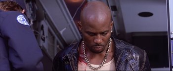 Movie still from “Cradle 2 the Grave” (2003), directed by Andrzej Bartkowiak – A man with a chain around his neck and head; Close Up shot, High angle