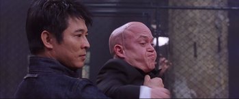 Movie still from “Cradle 2 the Grave” (2003), directed by Andrzej Bartkowiak – A man with a bald head is putting on a jacket; Close Up shot, Over the shoulder angle