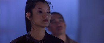 Movie still from “Cradle 2 the Grave” (2003), directed by Andrzej Bartkowiak – A woman standing next to a man in a room; Close Up shot, Over the shoulder angle