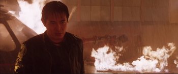 Movie still from “Cradle 2 the Grave” (2003), directed by Andrzej Bartkowiak – A man standing in front of a fire; Close Up shot, Low angle