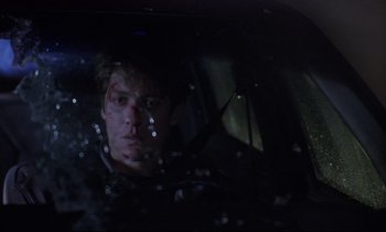 Movie still from “Crash” (1996), directed by David Cronenberg – A man with a bloody face sitting in the back of a car; Close Up shot, Over the shoulder angle