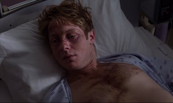 Movie still from “Crash” (1996), directed by David Cronenberg – A man with a black eye laying in a bed; Close Up shot, High angle