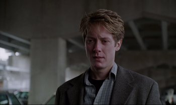 Movie still from “Crash” (1996), directed by David Cronenberg – A man in a jacket and shirt looking to his left; Close Up shot, Low angle