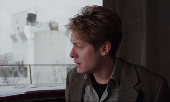 Movie still from “Crash” (1996), directed by David Cronenberg – A young man sitting in front of a window; Close Up shot, Over the shoulder angle