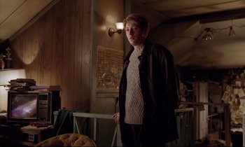 Movie still from “Crash” (1996), directed by David Cronenberg – A person standing in a room with a light on; Medium shot, Low angle