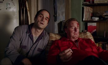 Movie still from “Crash” (1996), directed by David Cronenberg – Two men sitting next to each other on a couch; Medium shot, High angle