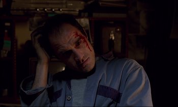 Movie still from “Crash” (1996), directed by David Cronenberg – A man with blood on his face is holding his head in his hands; Close Up shot, Low angle