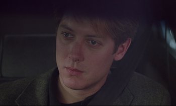 Movie still from “Crash” (1996), directed by David Cronenberg – A young man is looking into the distance; Close Up shot, Over the shoulder angle