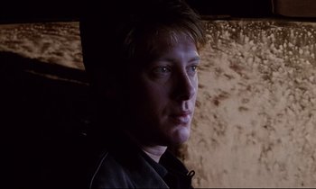 Movie still from “Crash” (1996), directed by David Cronenberg – A person in a dark room; Close Up shot, Low angle