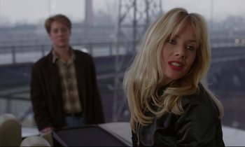Movie still from “Crash” (1996), directed by David Cronenberg – A woman with blonde hair and red lipstick in front of a man with blonde hair; Close Up shot, Over the shoulder angle
