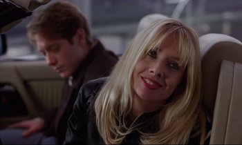 Movie still from “Crash” (1996), directed by David Cronenberg – A woman with blonde long hair and red lipstick; Close Up shot, Over the shoulder angle