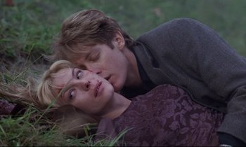 Movie still from “Crash” (1996), directed by David Cronenberg – A man and a woman laying in the grass; Close Up shot, High angle