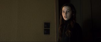 Movie still from “The Girl in the Spider's Web” (2018), directed by Fede Alvarez – A young girl standing in a dark room; Close Up shot, Low angle