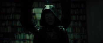 Movie still from “The Girl in the Spider's Web” (2018), directed by Fede Alvarez – A person wearing a hood in a dark room; Medium shot, Overhead angle