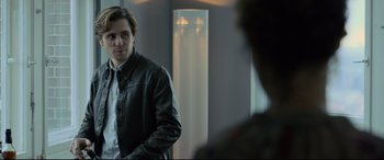 Movie still from “The Girl in the Spider's Web” (2018), directed by Fede Alvarez – A man standing in front of a mirror in a room; Medium shot, Over the shoulder angle