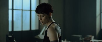Movie still from “The Girl in the Spider's Web” (2018), directed by Fede Alvarez – A woman smoking a cigarette while wearing a black shirt; Medium shot, Over the shoulder angle