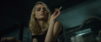 Movie still from “The Girl in the Spider's Web” (2018), directed by Fede Alvarez – A beautiful blonde woman holding a cigarette in her hand; Close Up shot, Low angle