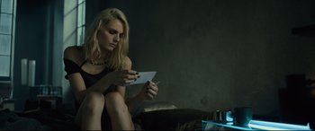 Movie still from “The Girl in the Spider's Web” (2018), directed by Fede Alvarez – A woman sitting on the ground writing on a piece of paper; Medium shot, Over the shoulder angle