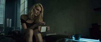 Movie still from “The Girl in the Spider's Web” (2018), directed by Fede Alvarez – A woman sitting on a couch holding a cell phone; Medium shot, Over the shoulder angle