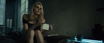 Movie still from “The Girl in the Spider's Web” (2018), directed by Fede Alvarez – A woman sitting on the ground holding a piece of paper; Medium shot, Over the shoulder angle