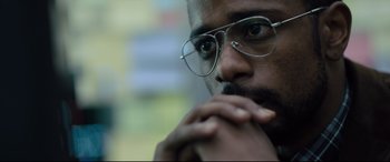 Movie still from “The Girl in the Spider's Web” (2018), directed by Fede Alvarez – A person wearing glasses with his hand on his chin; Close Up shot, Low angle