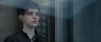 Movie still from “The Girl in the Spider's Web” (2018), directed by Fede Alvarez – A woman standing in front of a glass window; Close Up shot, Over the shoulder angle