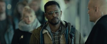 Movie still from “The Girl in the Spider's Web” (2018), directed by Fede Alvarez – A person wearing glasses and a jacket; Close Up shot, Over the shoulder angle