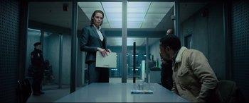 Movie still from “The Girl in the Spider's Web” (2018), directed by Fede Alvarez – A woman in a business suit holding a computer in front of two men; Medium shot, Low angle