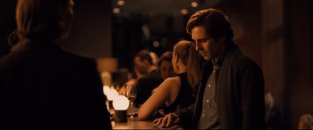 Movie still from “The Girl in the Spider's Web” (2018), directed by Fede Alvarez – A group of people sitting at a table with candles; Medium shot, Over the shoulder angle
