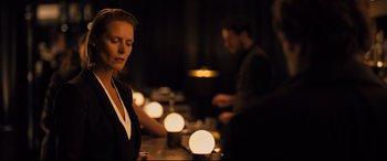 Movie still from “The Girl in the Spider's Web” (2018), directed by Fede Alvarez – A woman sitting in front of a group of candles; Medium shot, Over the shoulder angle