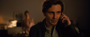 Movie still from “The Girl in the Spider's Web” (2018), directed by Fede Alvarez – A young man is talking on a cell phone; Close Up shot, Over the shoulder angle