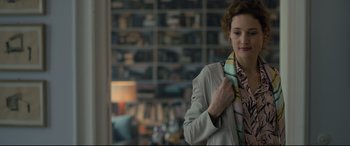 Movie still from “The Girl in the Spider's Web” (2018), directed by Fede Alvarez – A woman in a white jacket is tying a neck tie; Medium shot, Over the shoulder angle