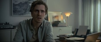 Movie still from “The Girl in the Spider's Web” (2018), directed by Fede Alvarez – A man sitting at a table in front of a lamp; Close Up shot, Over the shoulder angle