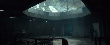 Movie still from “The Girl in the Spider's Web” (2018), directed by Fede Alvarez – A person standing in a room with a large ceiling; Extreme Wide shot, Low angle
