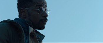 Movie still from “The Girl in the Spider's Web” (2018), directed by Fede Alvarez – A person wearing glasses and a jacket; Close Up shot, Low angle