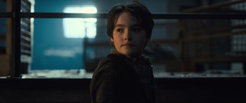 Movie still from “The Girl in the Spider's Web” (2018), directed by Fede Alvarez – A young boy is standing in a dark room; Close Up shot, Low angle