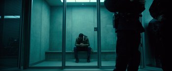 Movie still from “The Girl in the Spider's Web” (2018), directed by Fede Alvarez – A man sitting on a bench in a room; Wide shot, Low angle