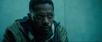 Movie still from “The Girl in the Spider's Web” (2018), directed by Fede Alvarez – A person wearing glasses and a jacket; Close Up shot, Low angle