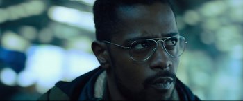 Movie still from “The Girl in the Spider's Web” (2018), directed by Fede Alvarez – A person wearing glasses and a jacket; Close Up shot, Over the shoulder angle