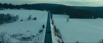 Movie still from “The Girl in the Spider's Web” (2018), directed by Fede Alvarez – An aerial view of a road in the middle of a snow covered field; Extreme Wide shot, High angle
