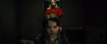 Movie still from “The Girl in the Spider's Web” (2018), directed by Fede Alvarez – A woman in a red dress standing in front of a boy; Medium shot, Low angle