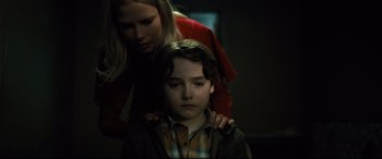 Movie still from “The Girl in the Spider's Web” (2018), directed by Fede Alvarez – A woman is helping a young boy with his head; Close Up shot, Over the shoulder angle