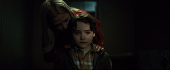 Movie still from “The Girl in the Spider's Web” (2018), directed by Fede Alvarez – A woman is helping a young boy with his arm around his shoulder; Close Up shot, Over the shoulder angle