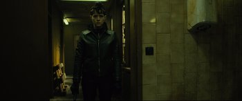 Movie still from “The Girl in the Spider's Web” (2018), directed by Fede Alvarez – A man in a leather jacket standing next to a door; Medium shot, Low angle