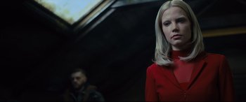 Movie still from “The Girl in the Spider's Web” (2018), directed by Fede Alvarez – A woman in a red dress standing next to a man in a black suit; Close Up shot, Low angle