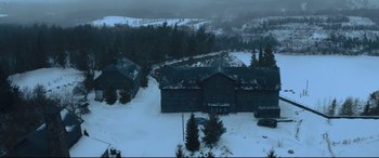 Movie still from “The Girl in the Spider's Web” (2018), directed by Fede Alvarez – An aerial view of a snowy landscape with a large building; Extreme Wide shot, High angle