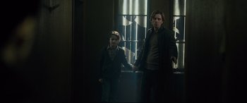 Movie still from “The Girl in the Spider's Web” (2018), directed by Fede Alvarez – A man and a boy standing next to each other holding hands; Medium shot, Low angle