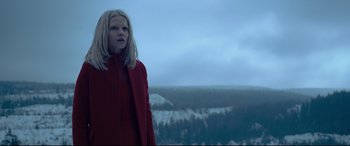 Movie still from “The Girl in the Spider's Web” (2018), directed by Fede Alvarez – A woman in a red coat standing in front of a mountain range; Medium shot, Low angle