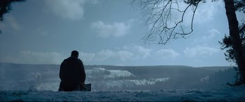 Movie still from “The Girl in the Spider's Web” (2018), directed by Fede Alvarez – A person sitting on a bench in the snow; Wide shot, Low angle