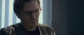 Movie still from “The Girl in the Spider's Web” (2018), directed by Fede Alvarez – A person wearing glasses and a jacket; Close Up shot, Over the shoulder angle